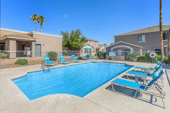 A swimming pool with blue water and lounge chairs.